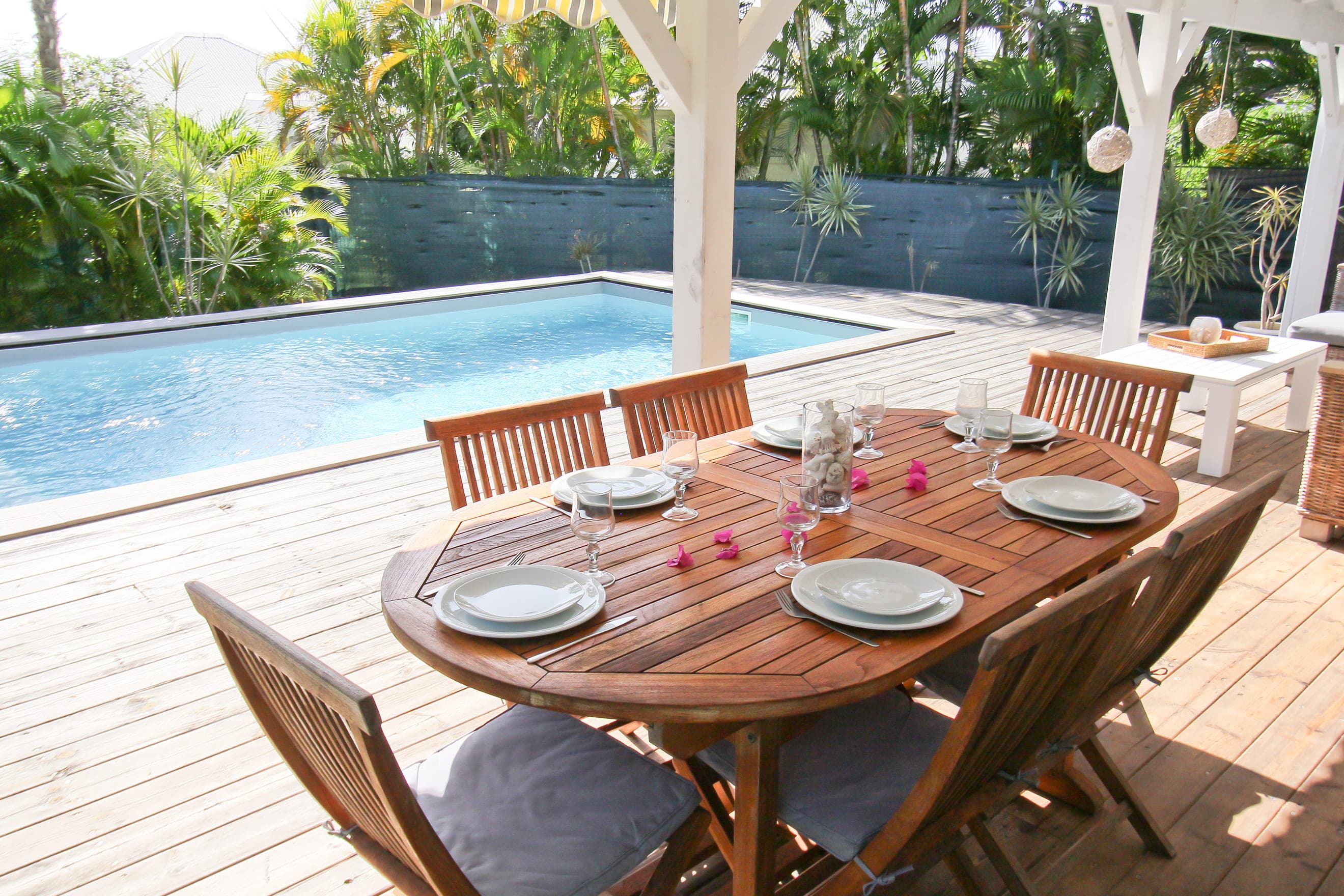 Table de repas dressée sur la terrasse de la Villa Alizé, au bord de la piscine