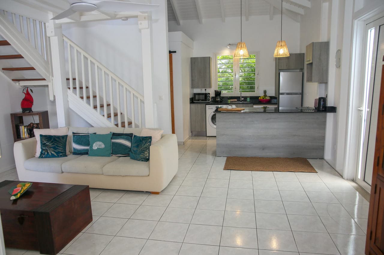 Salon de la Villa Alizé sous l’escalier de la mezzanine, ouvert sur la cuisine américaine