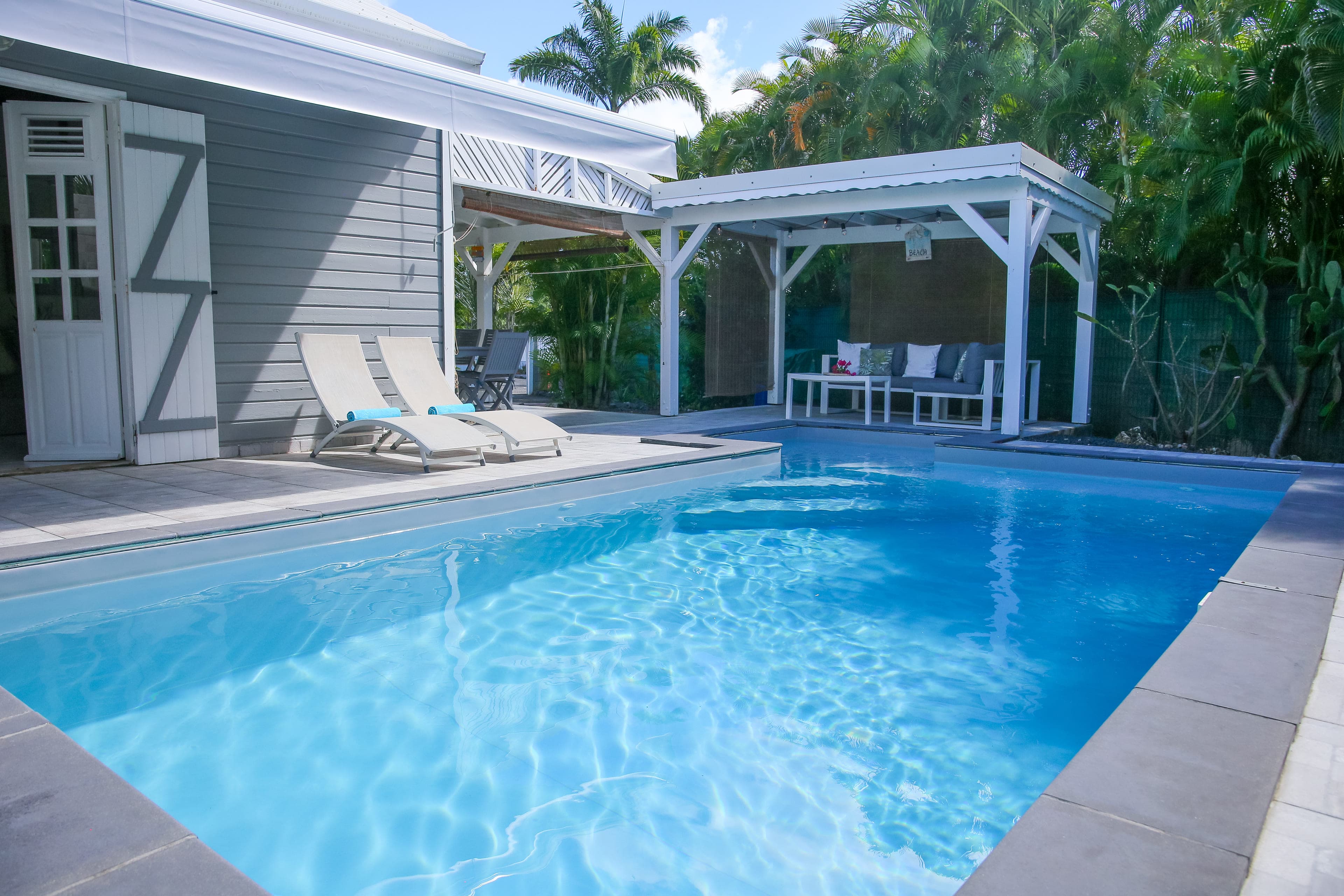 La piscine de la Villa Bahia au premier plan, la pergola et la terrasse couverte au fond