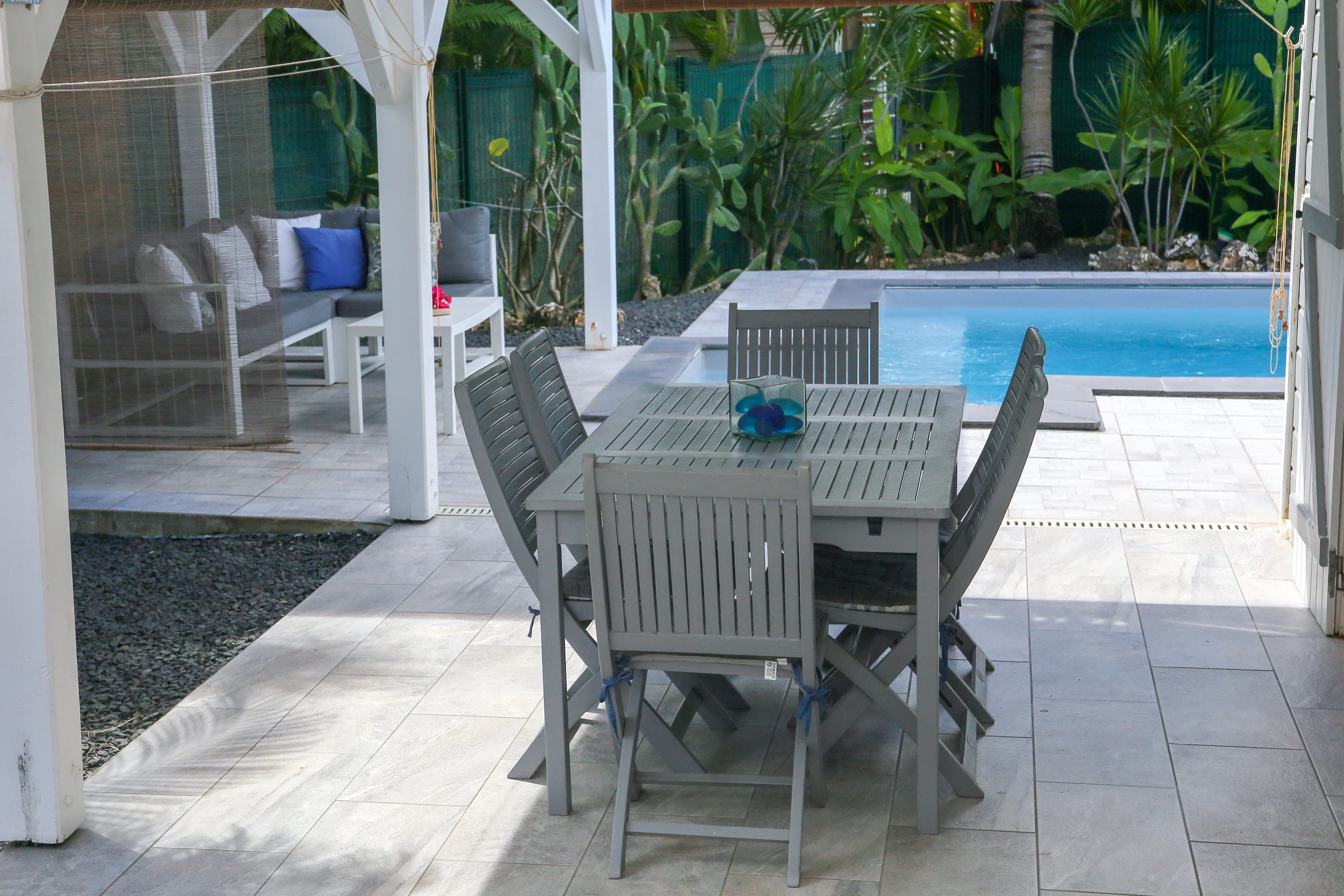 Le patio de la Villa Bahia et son store de bambou, vus depuis la table de la terrasse couverte